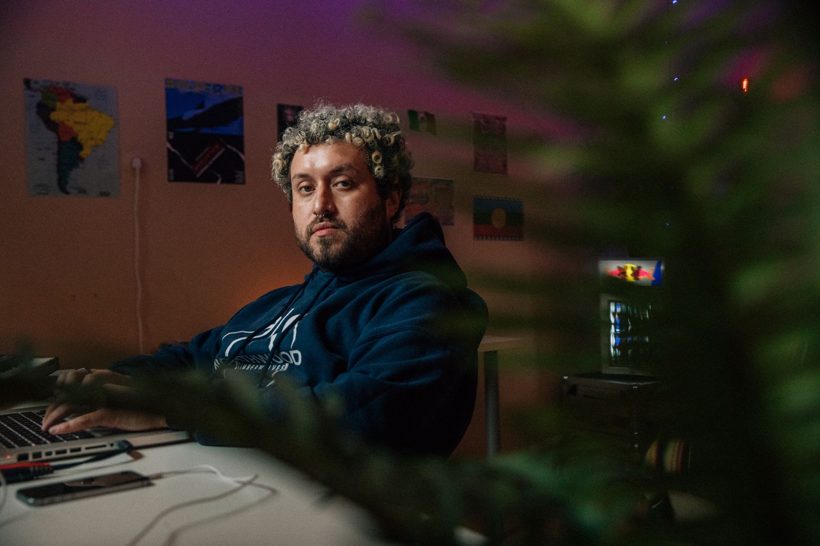 DJ at his home studio desk with a synthesizer and laptop
