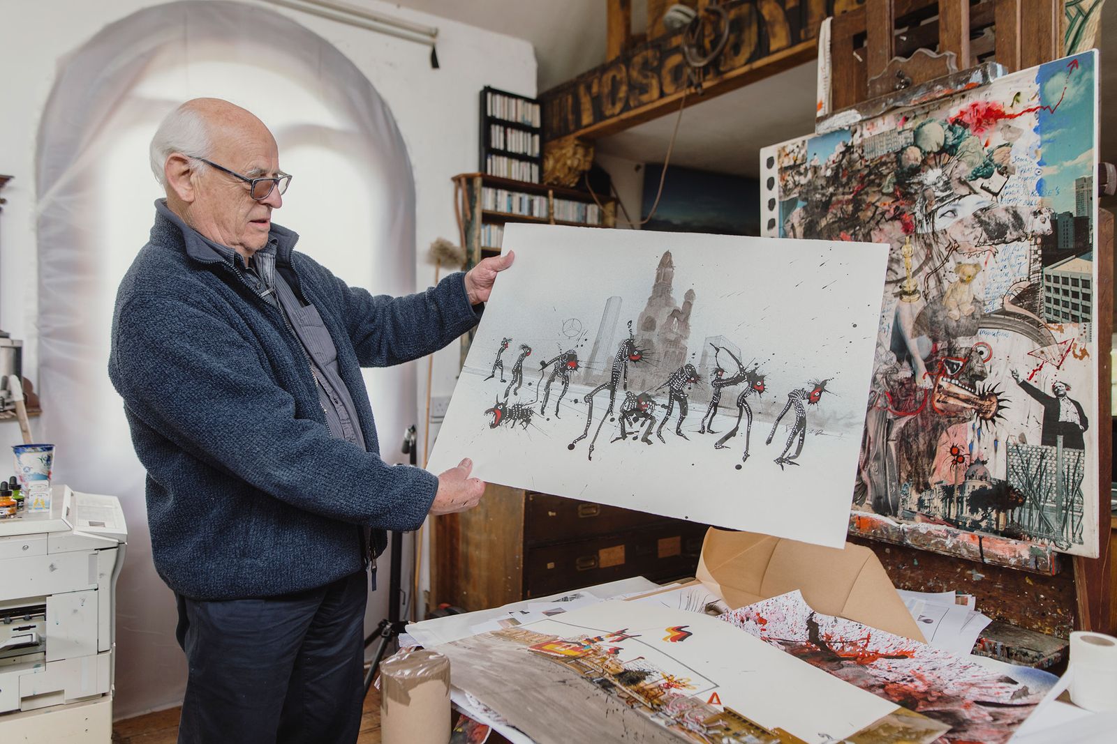 Illustrator holding up an ink drawing in his studio