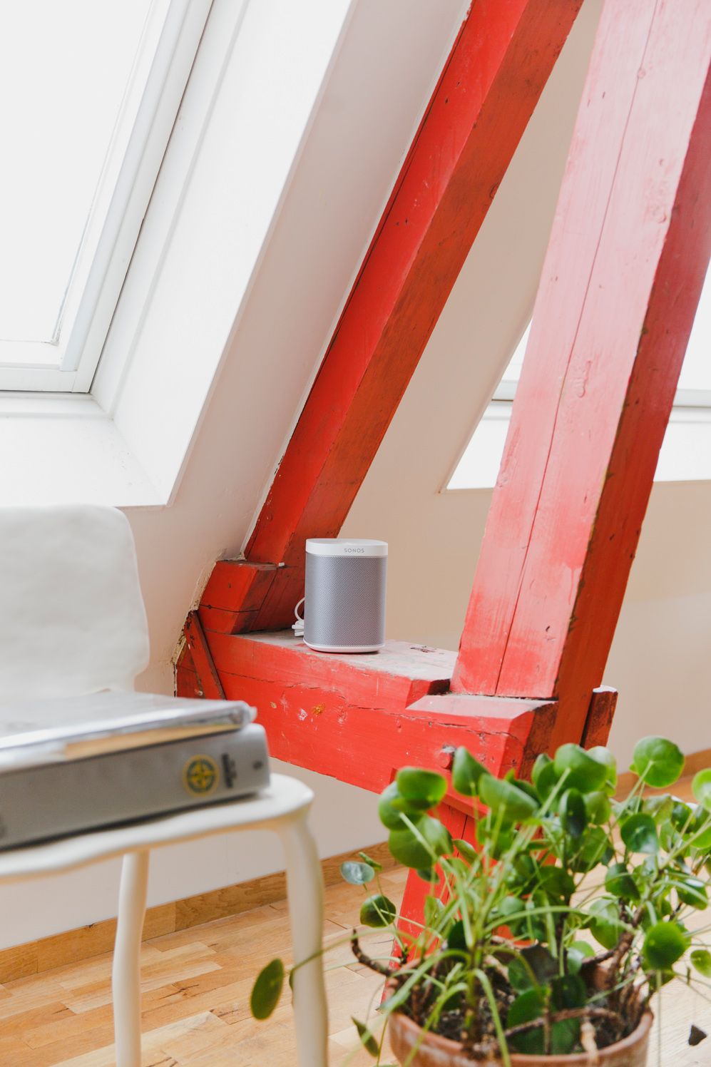 White Sonos One on a red roof beam above a plant in an Amsterdam attic