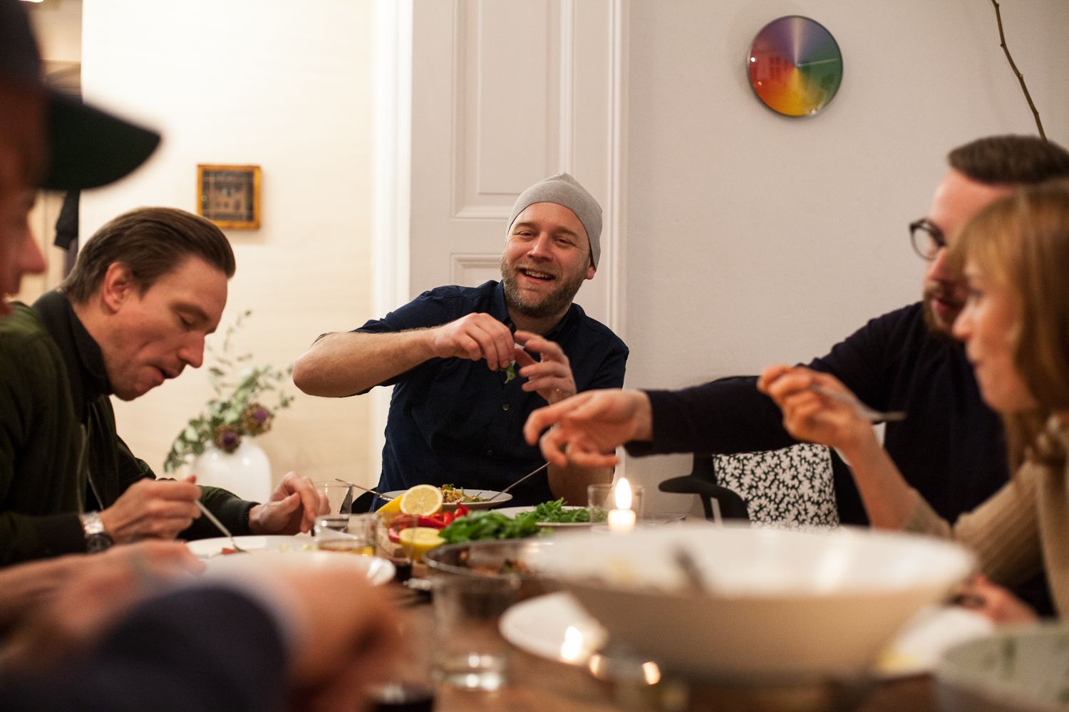 Friends laughing around a candlelit dinner table