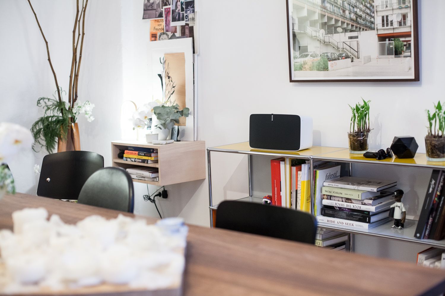 Black Sonos speaker on a shelf of art books in a white room