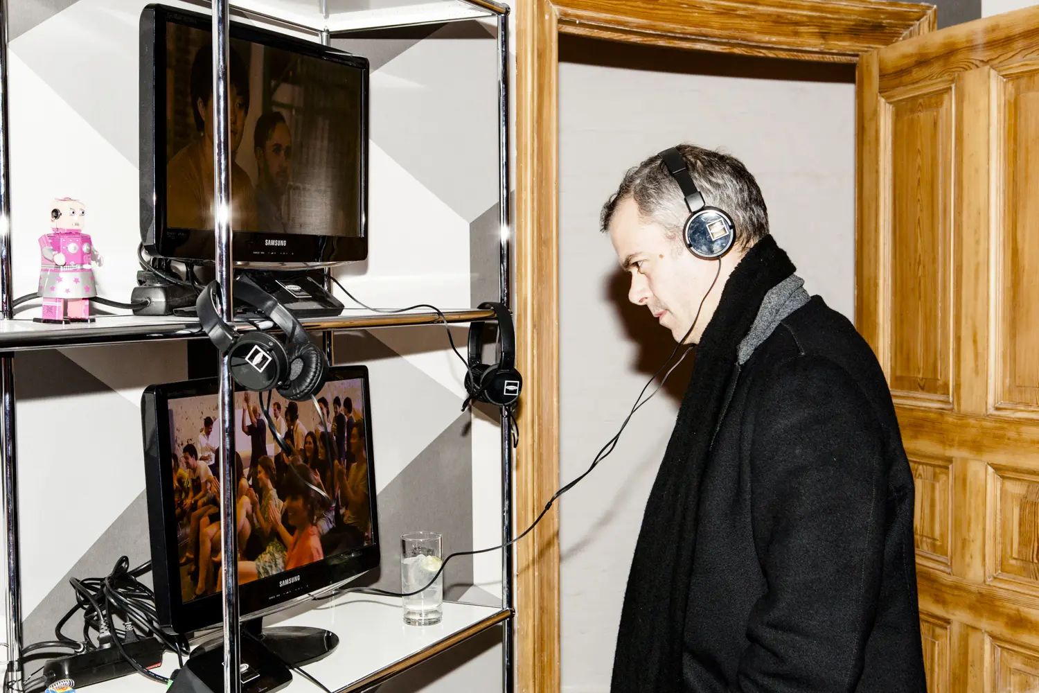 Guest with headphones at a USM shelf of screens showing student work, USM project50 anniversary event