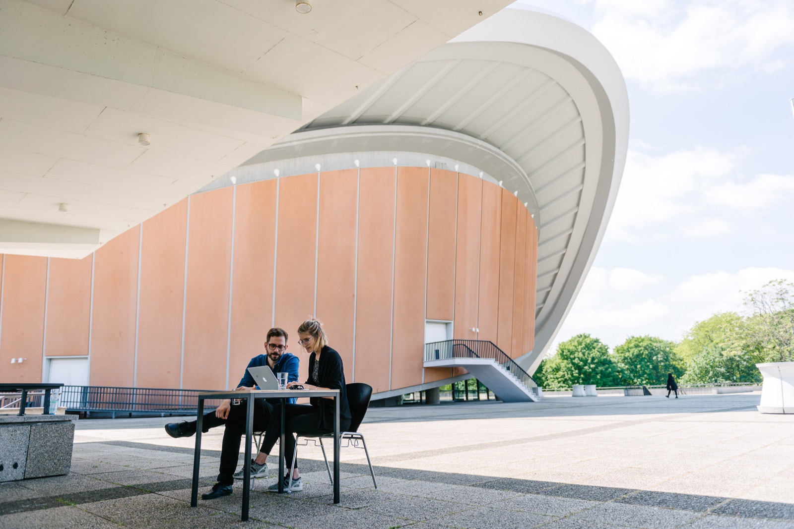 Birgit Palma and Daniel Triendl working at a small table on the terrace of Haus der Kulturen der Welt