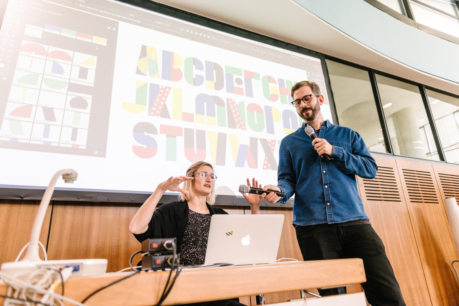 Birgit Palma and Daniel Triendl on stage at the Modular Lettering workshop, TYPO Berlin 2017, a modular alphabet projected behind them