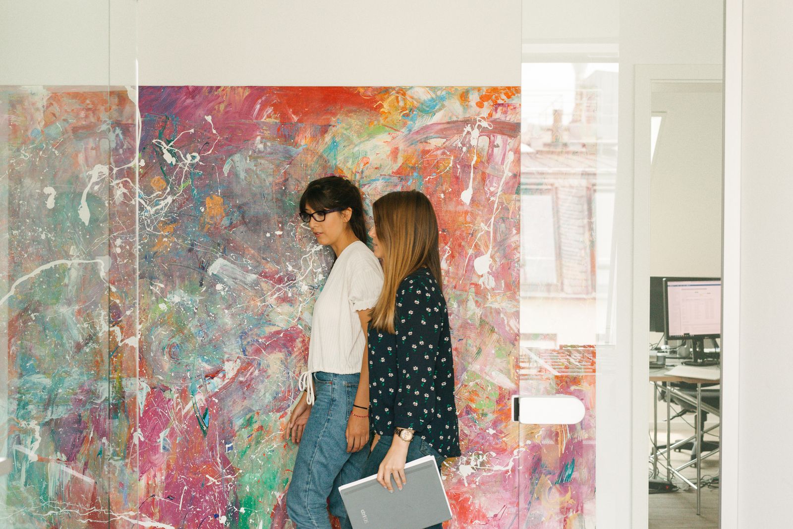 Two colleagues walking past a large colourful painting in the ctrl QS office