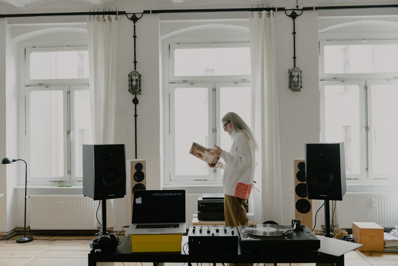 DJ reading a record sleeve between speakers in her bright Berlin loft