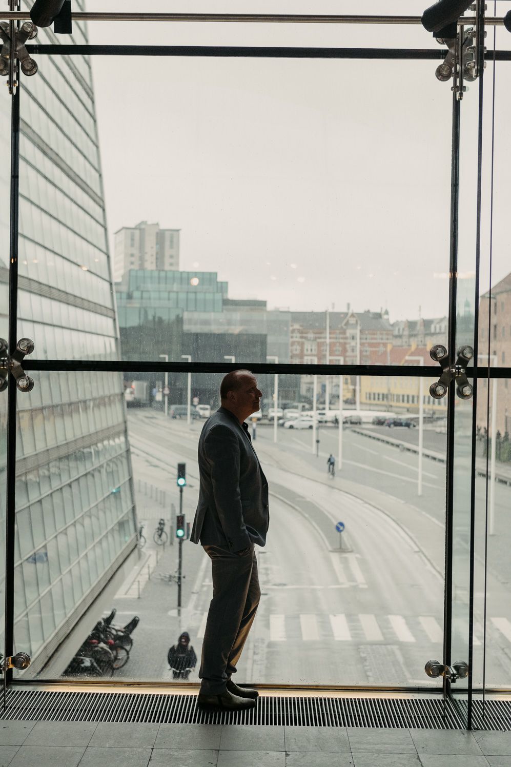 Sound researcher standing at a tall glass facade overlooking the city