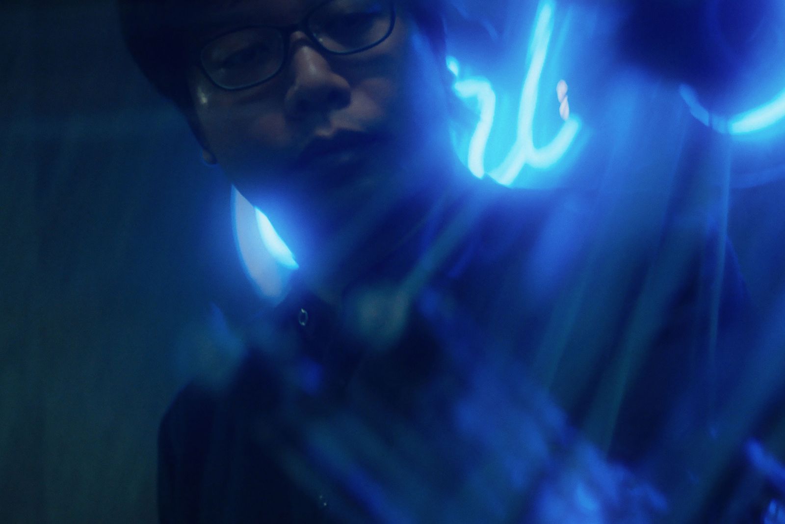 Face lit by blue light from a light installation, film still
