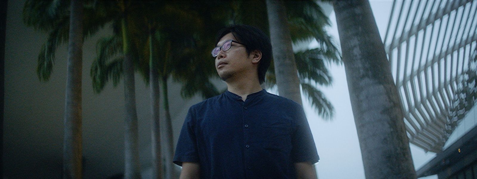 Wide portrait of the gadget maker outdoors among palm trees in Singapore