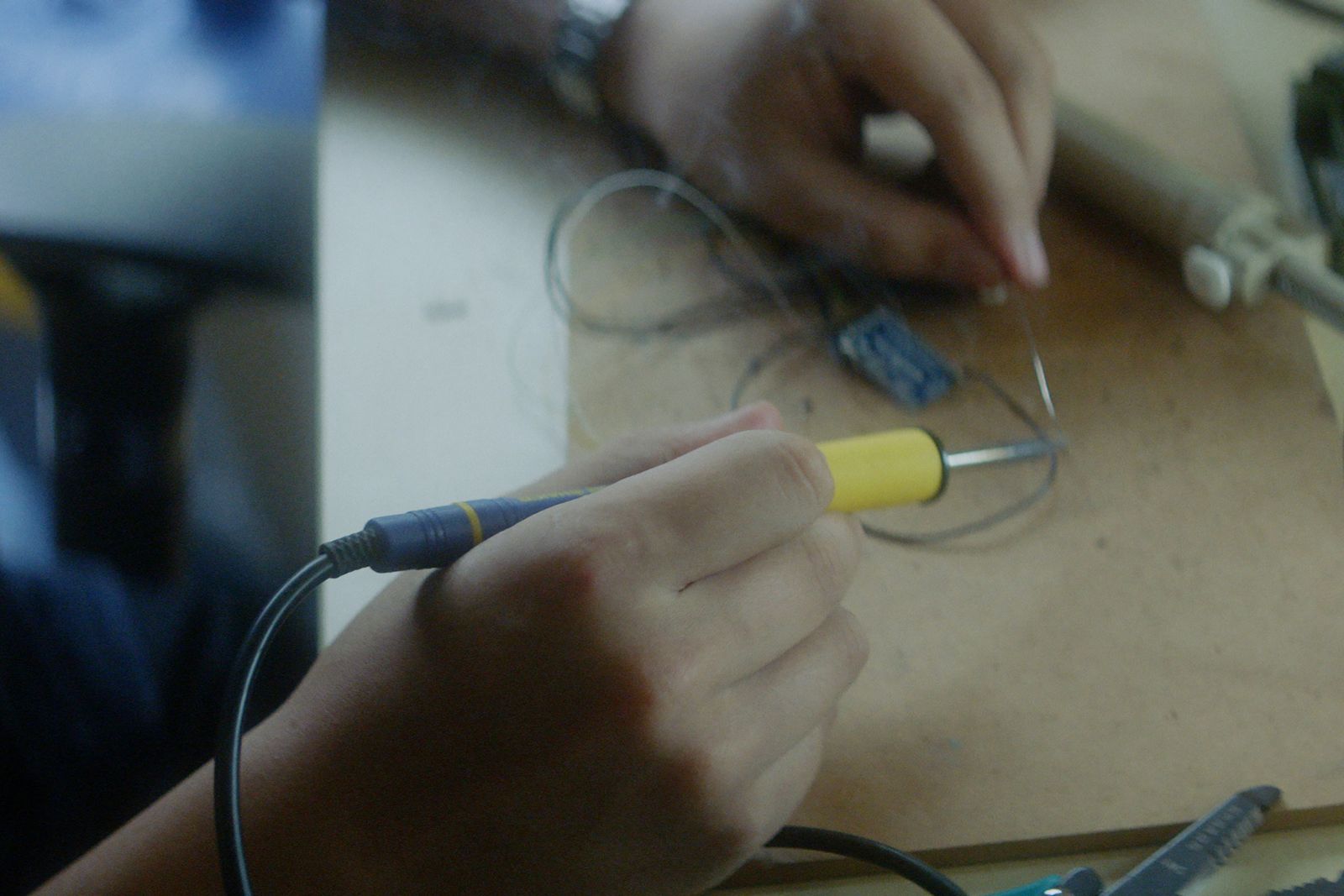 Close-up of hands soldering a small circuit board