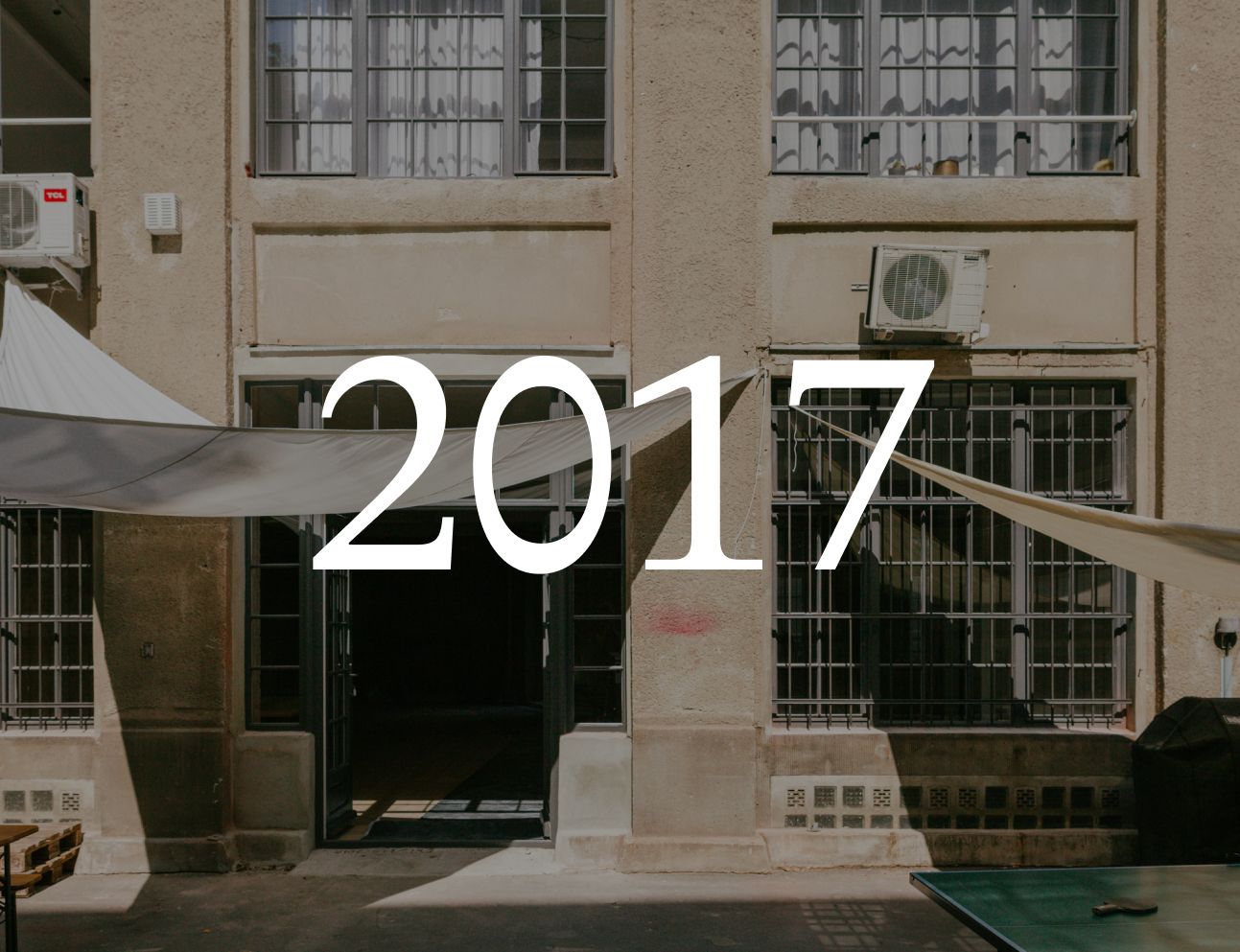 Courtyard facade of an industrial building with a sun sail, with the year 2017 set over the image