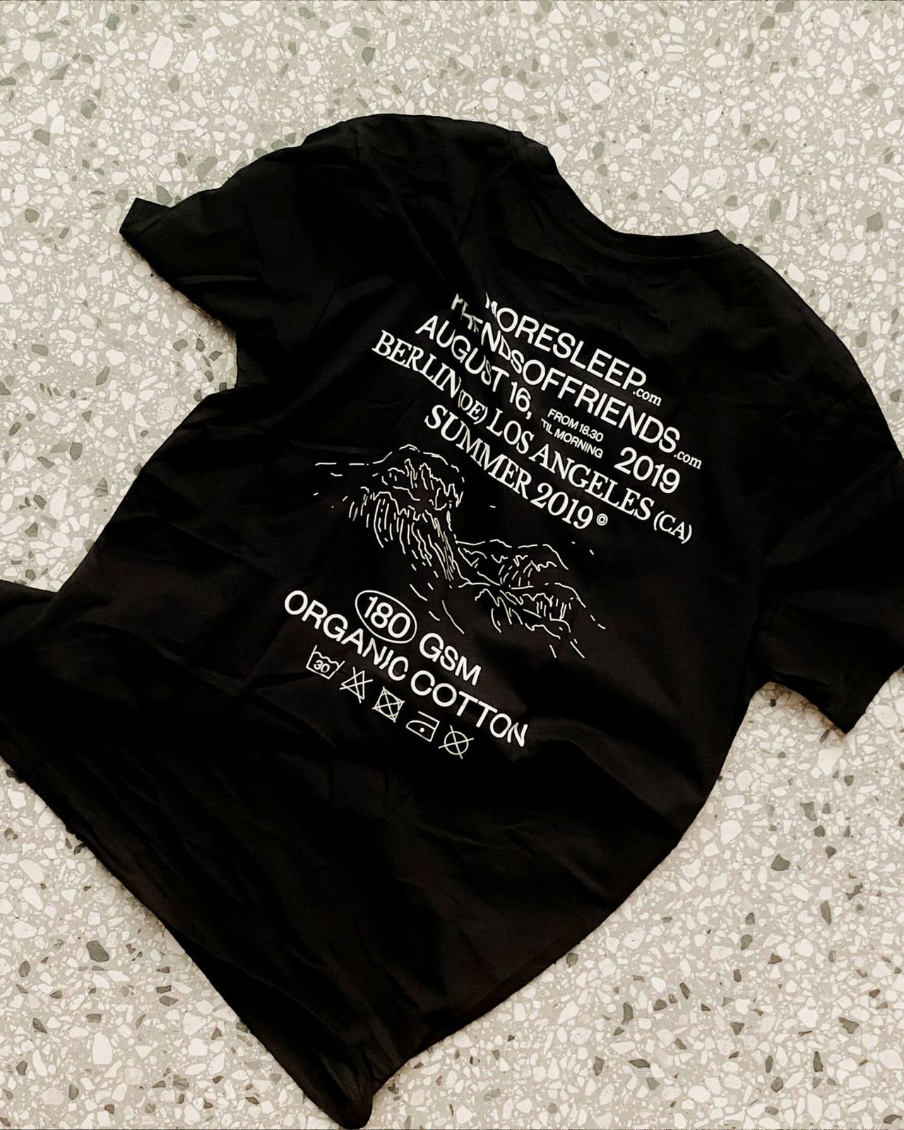 Black MoreSleep and Friends of Friends summer 2019 T-shirt lying flat on terrazzo
