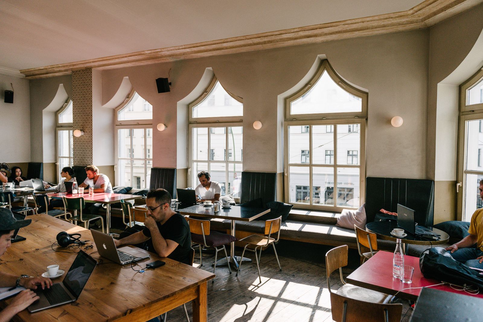 Tall arched windows and long tables in the coworking cafe at Rosenthaler Platz, Berlin