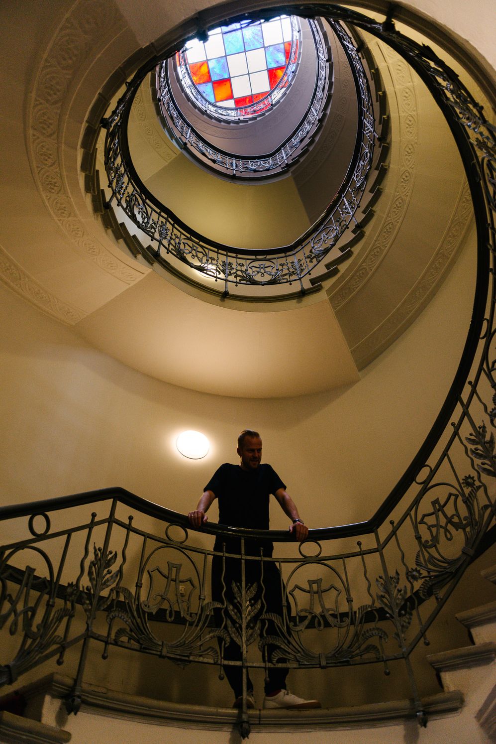 Looking up a spiral staircase in an old Berlin building, a figure on the landing