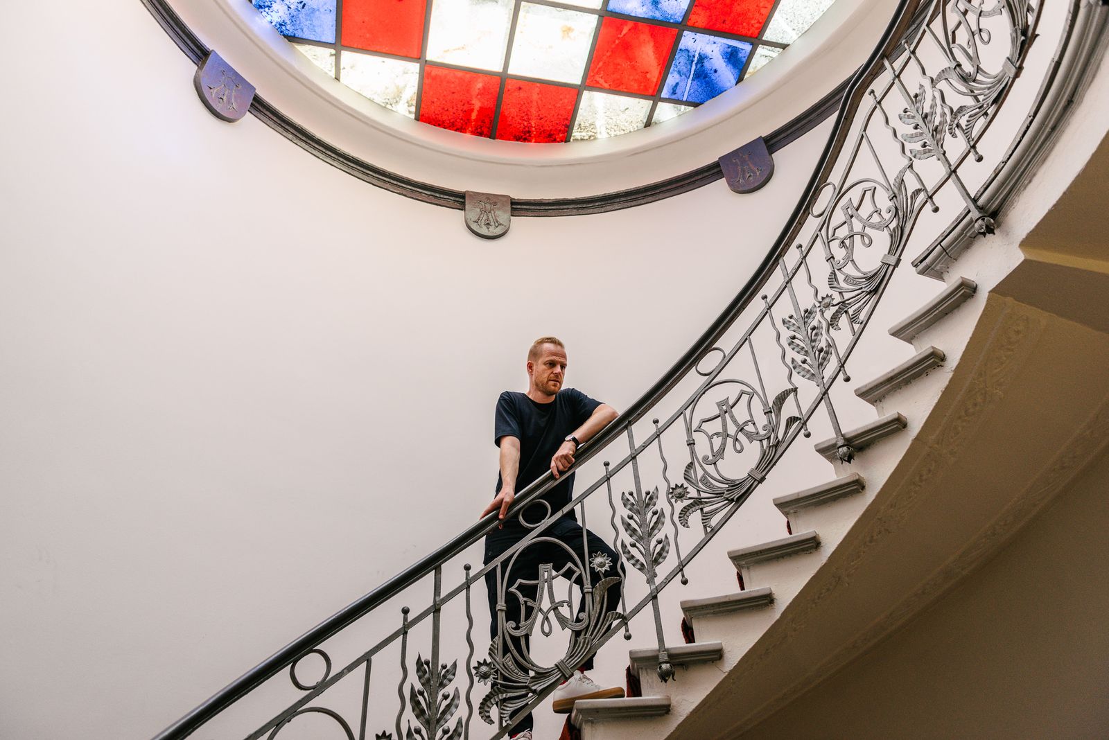 Entrepreneur on a curved stairwell under a stained glass skylight in Berlin