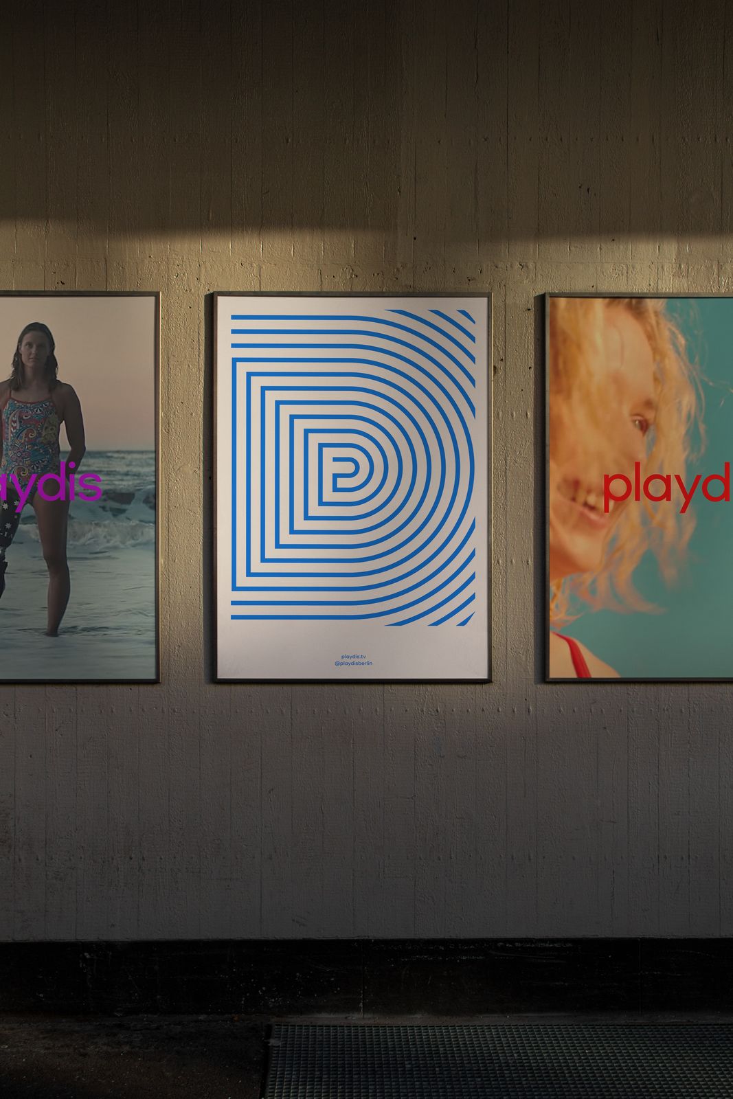 Playdis poster series on a dark wall, the P mark drawn in concentric blue lines