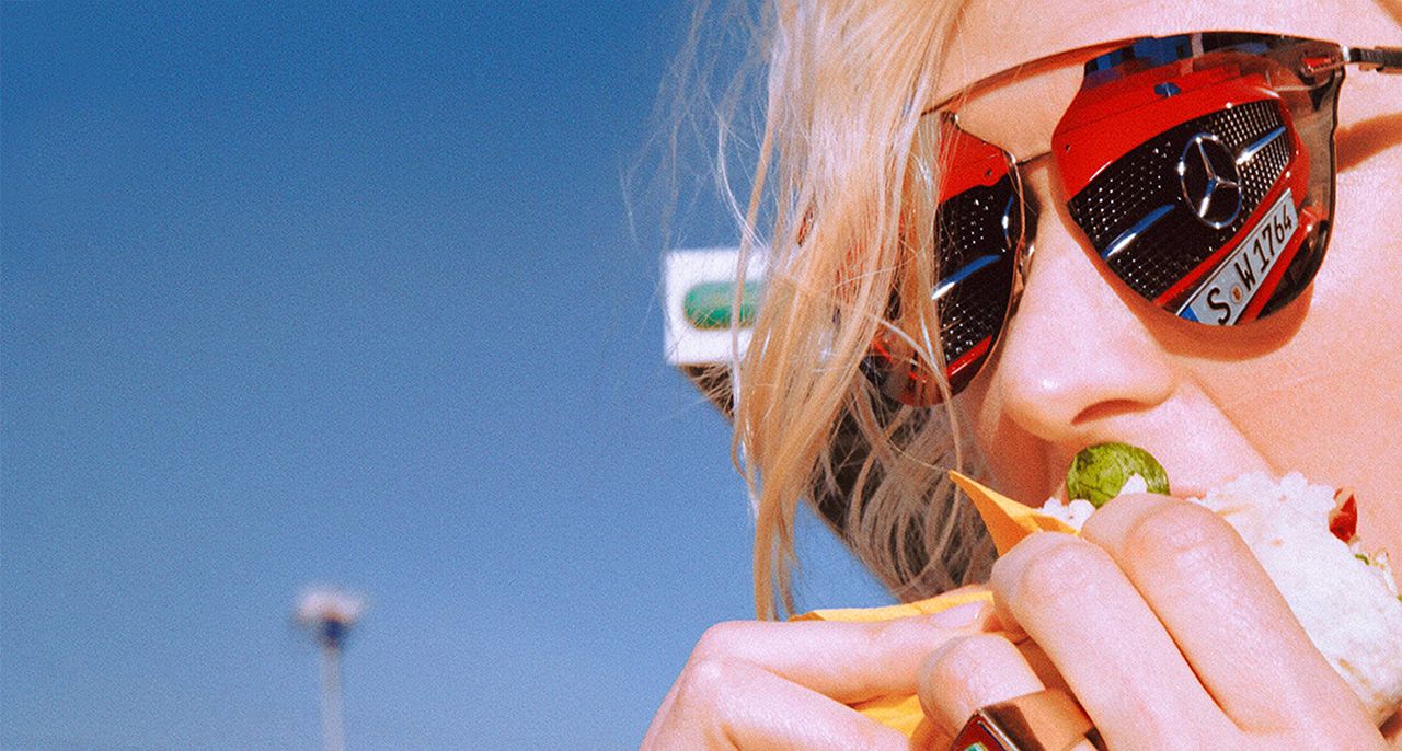 Playdis website header image, close-up of a woman in red sunglasses eating