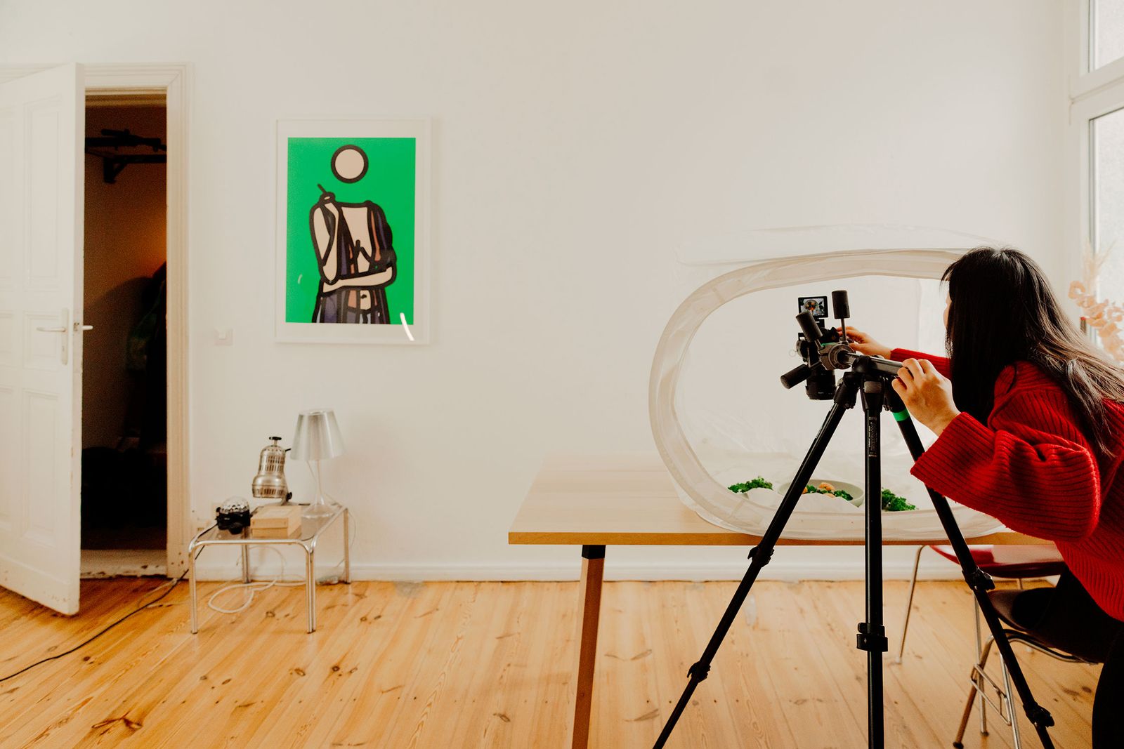Chi You filming a dish on a tripod camera in her flat