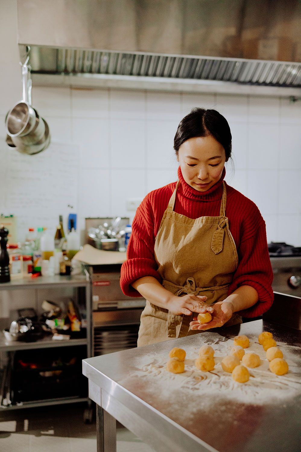Chi You shaping dough balls in a professional kitchen