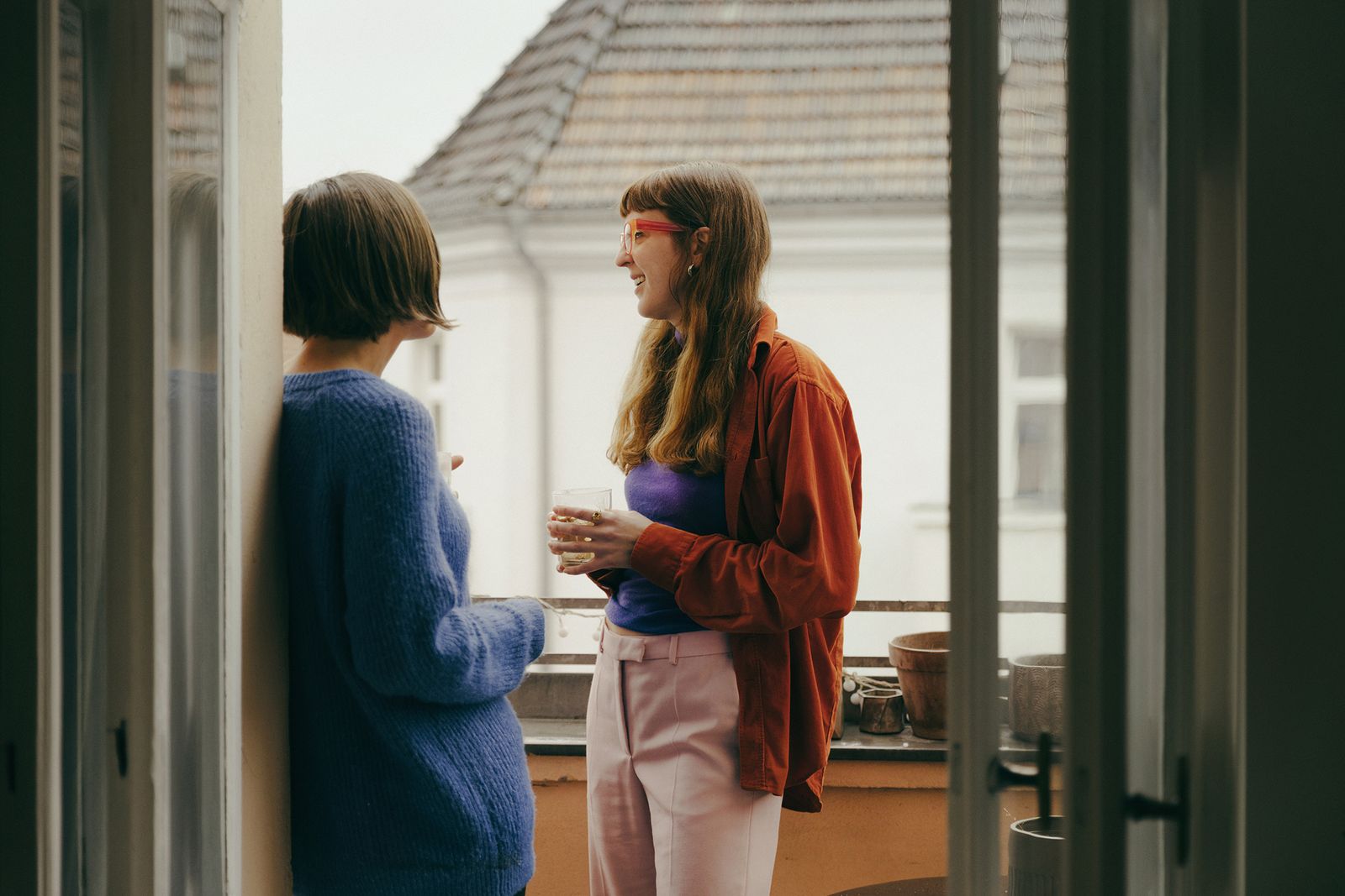 The Journal Collective founders talking at an open balcony door in a Berlin flat