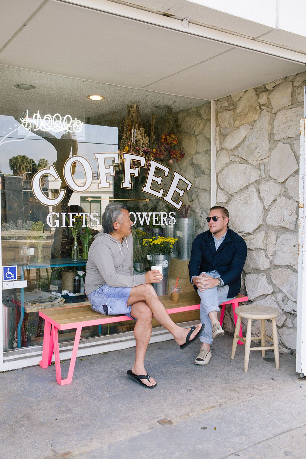 Two people on a pink bench outside a coffee and flower shop in Venice