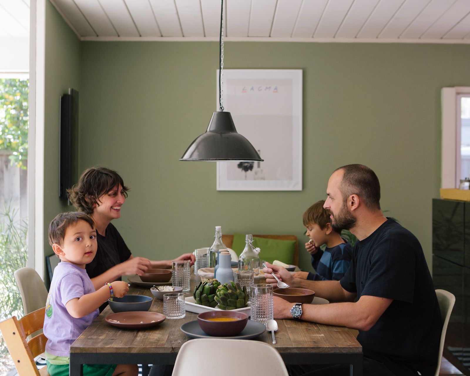 Family dinner under a pendant lamp in a green dining room