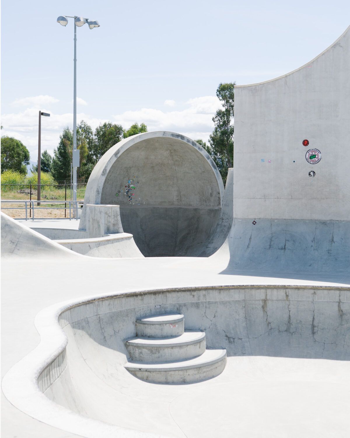 Empty concrete skate bowl with steps under a bright sky in San Jose