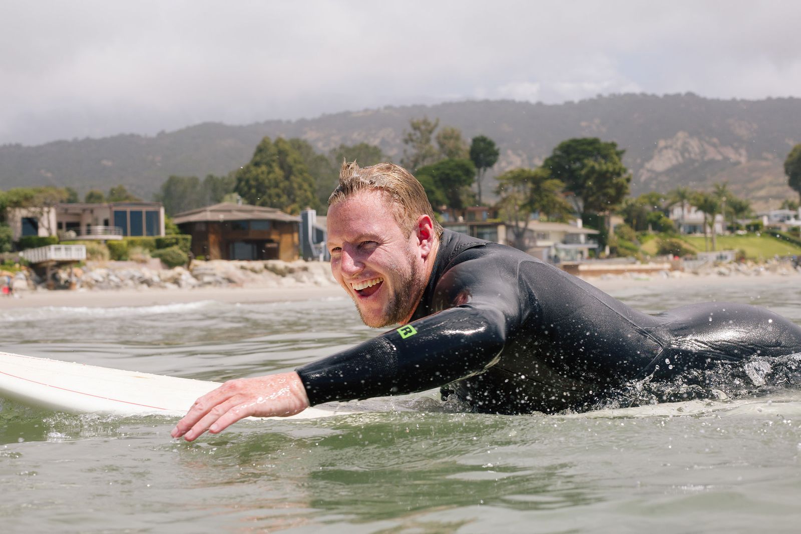 Surfer laughing as he paddles out on an evening surf near Santa Barbara