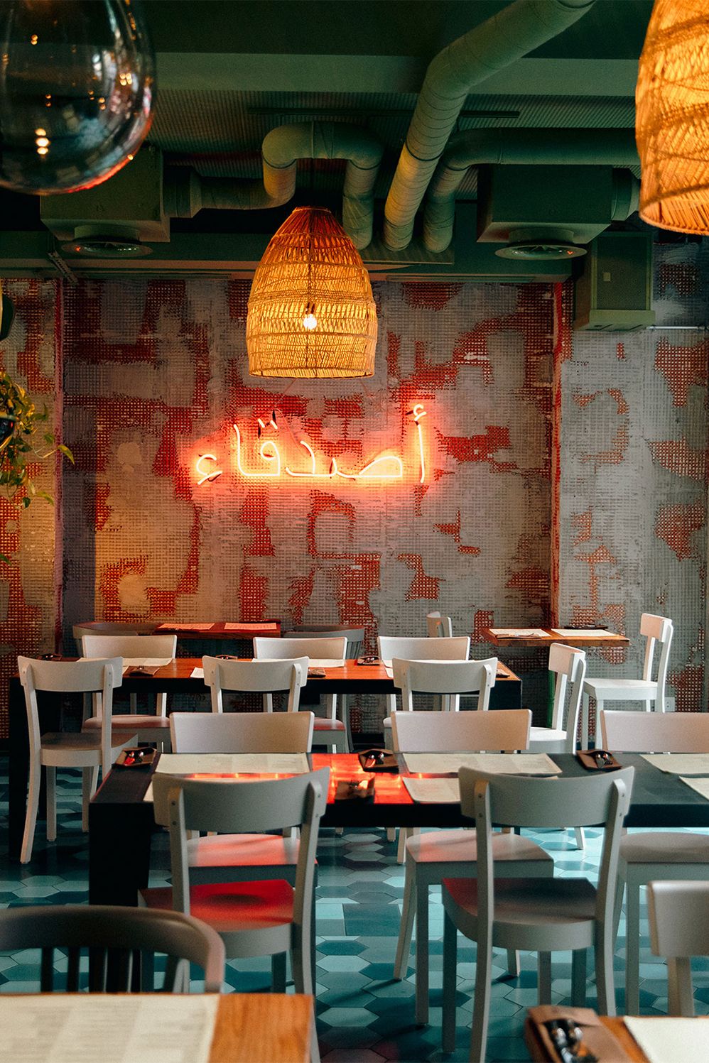 Restaurant interior with a red neon sign, rattan lamps and white chairs