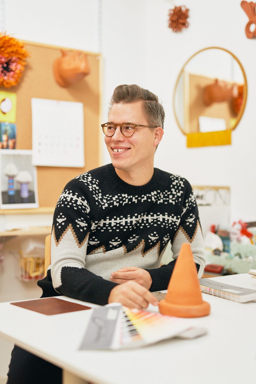 Designer smiling at his desk next to an orange ceramic cone