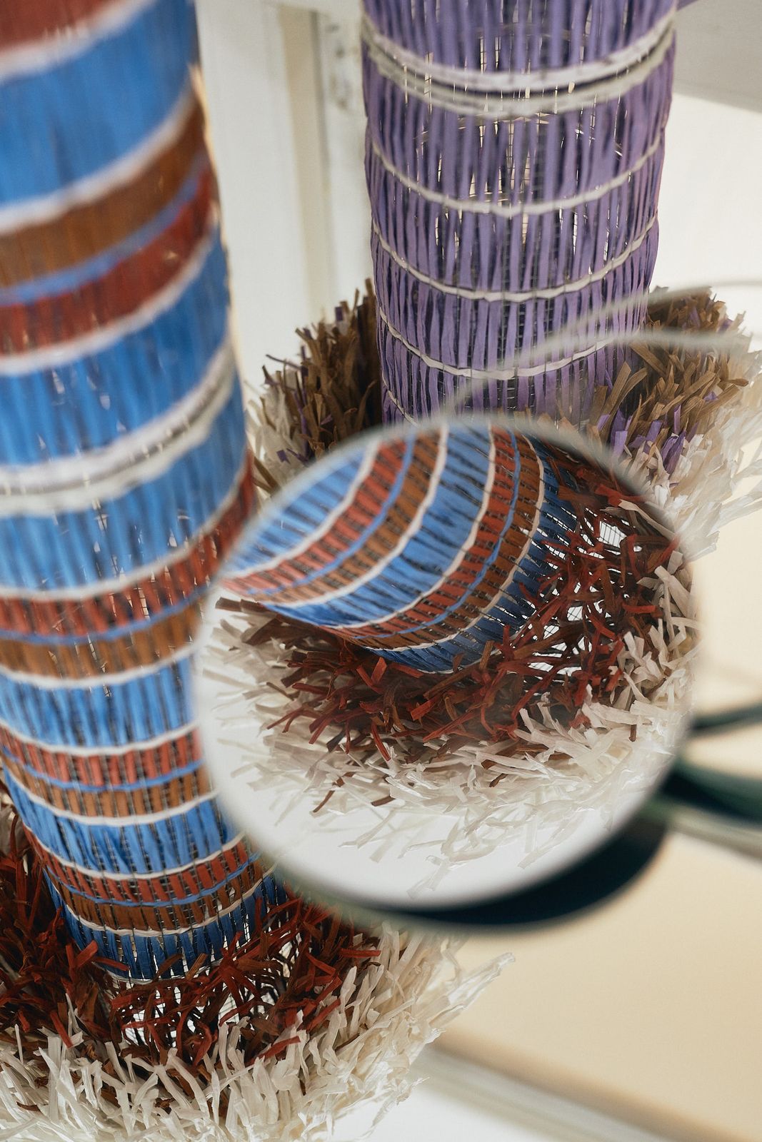 Magnifying glass over a woven striped object with a fringed base