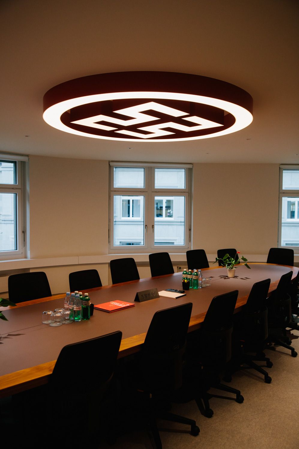 Boardroom with a long table under a bespoke illuminated logo ring, Zurich