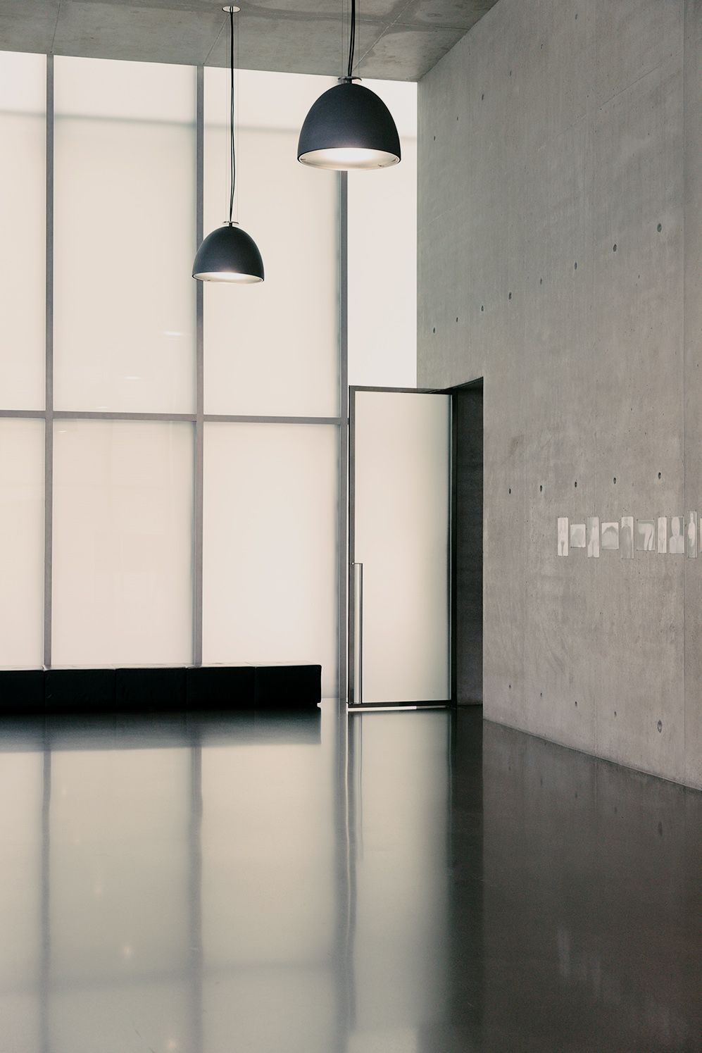 Concrete hall with frosted glass walls and black pendant lamps, Vorarlberg