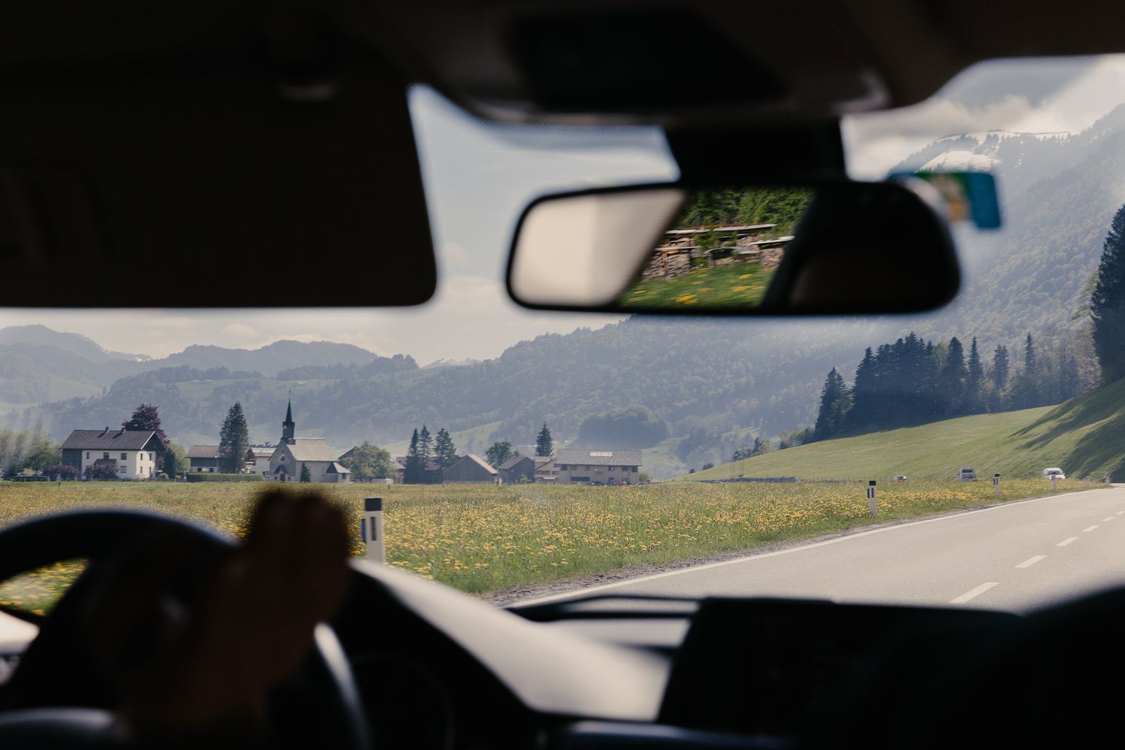 Driving through a green Vorarlberg valley towards a village